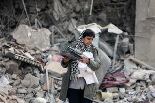 An Iranian woman collects belongings from the rubble of a destroyed residential building in Tehran on 12 March 2026